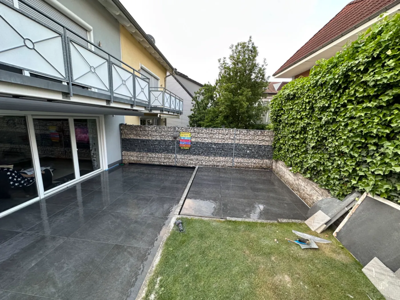 Terrasse mit großformatigen Platten und Gabionen-Sichtschutz