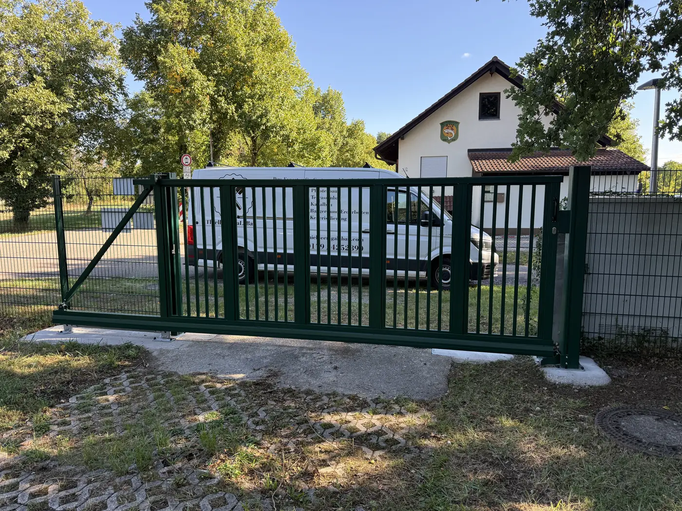 Dunkelgrünes Schiebetor an einer neu gesetzten Zaunanlage