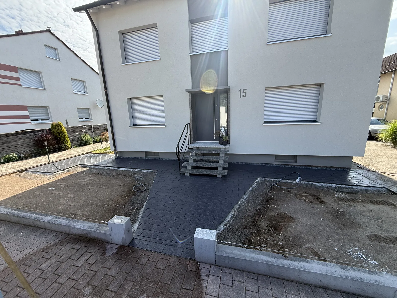 Dunkel gepflasterte Hoffläche vor einem Mehrfamilienhaus